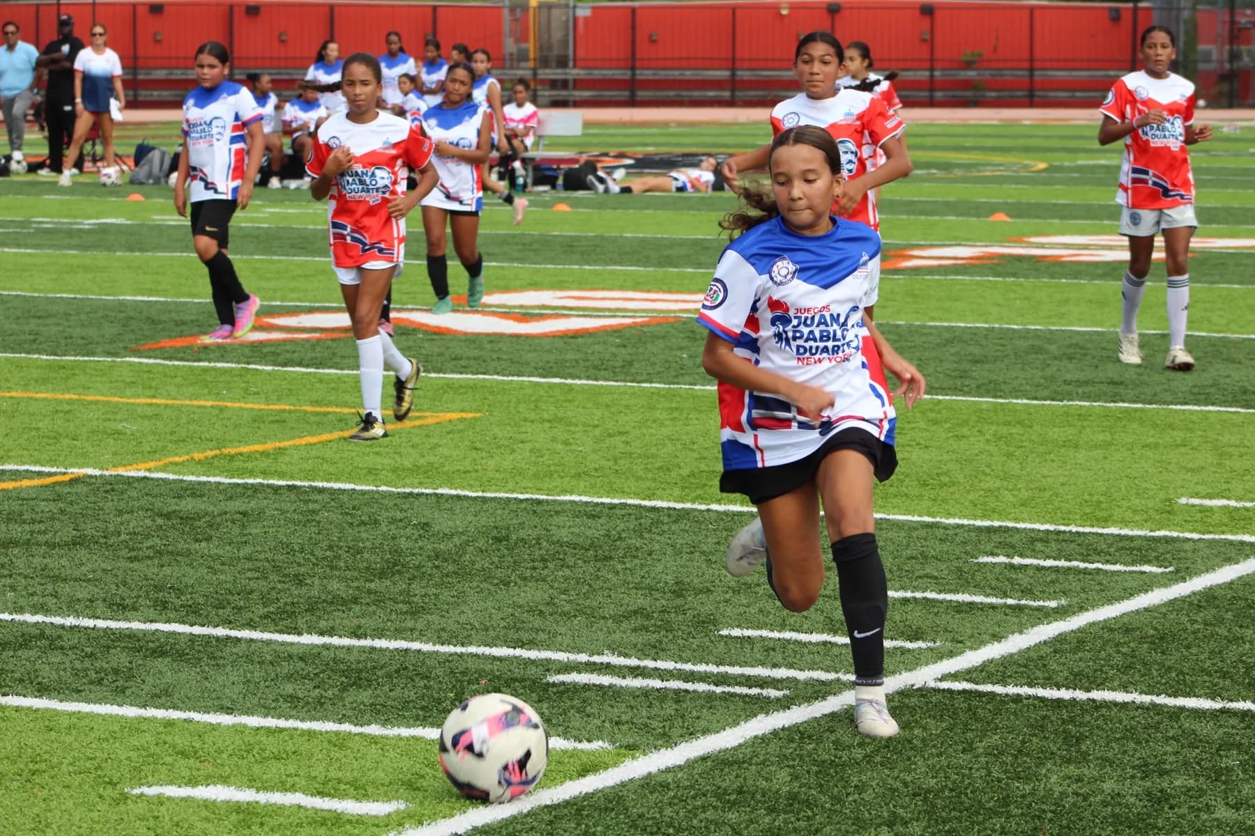 A player drives forward with the ball at her feet as the defense closes in.