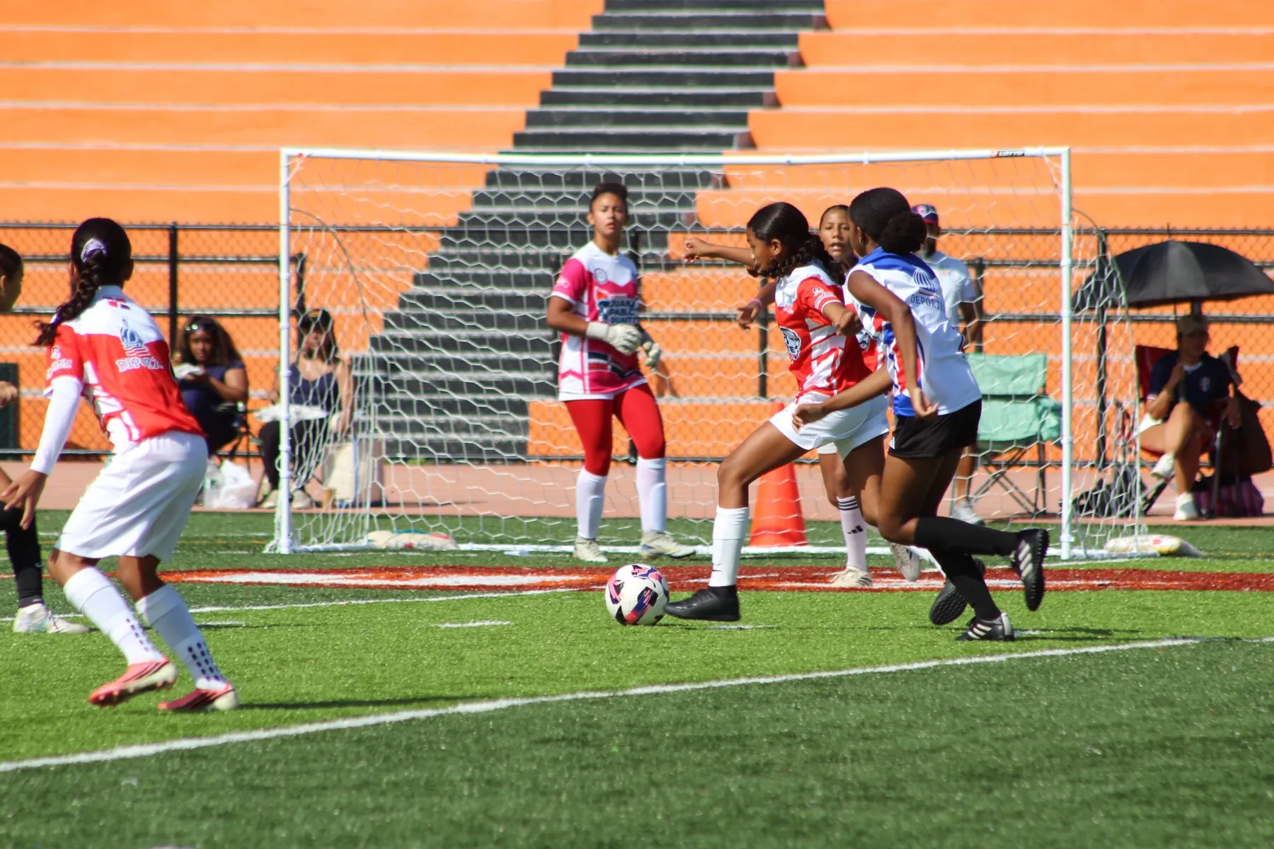 Players converge in front of goal as a shot is struck at the George Washington campus field.