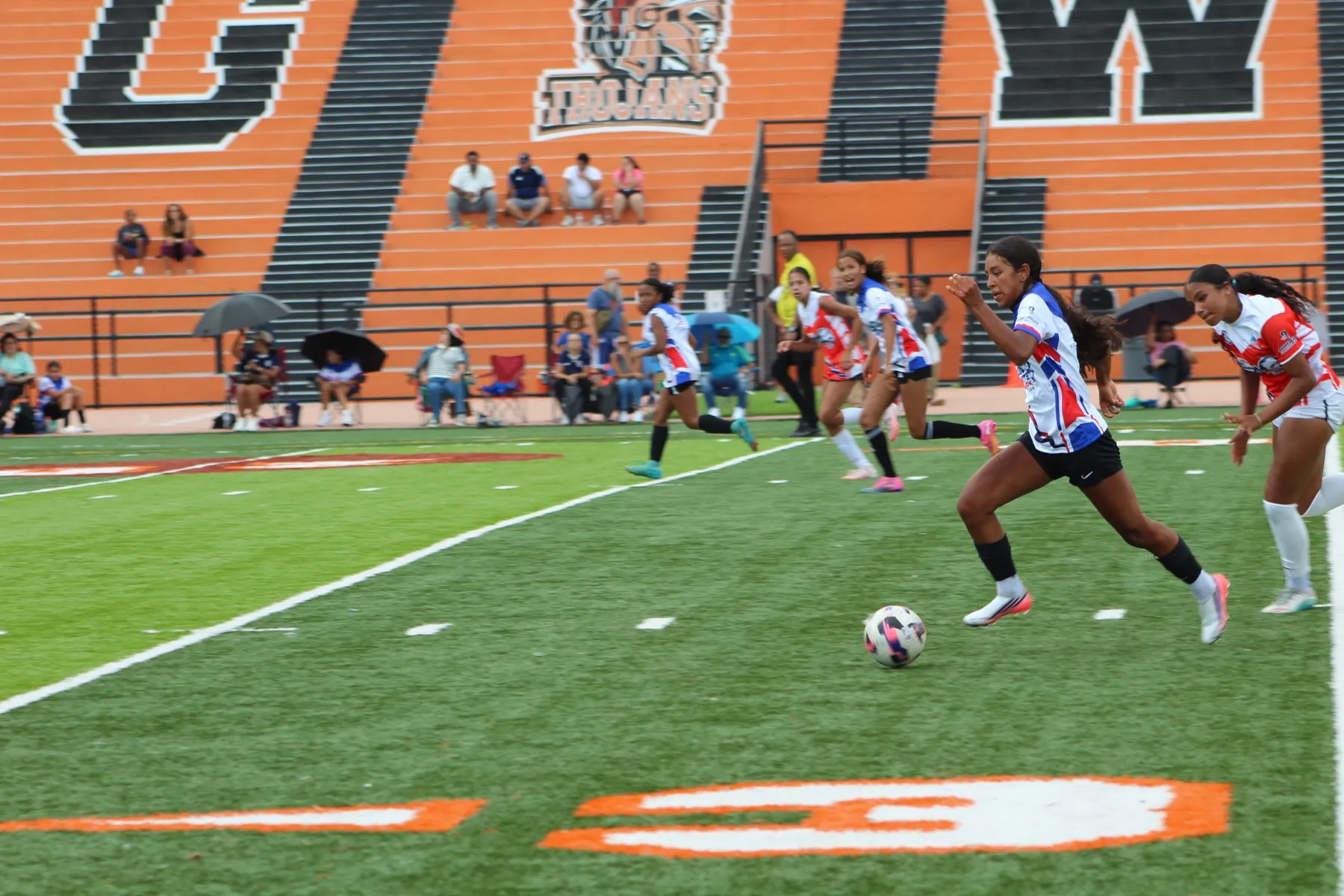 A New York player carries the ball upfield in front of the George Washington Trojans wall.