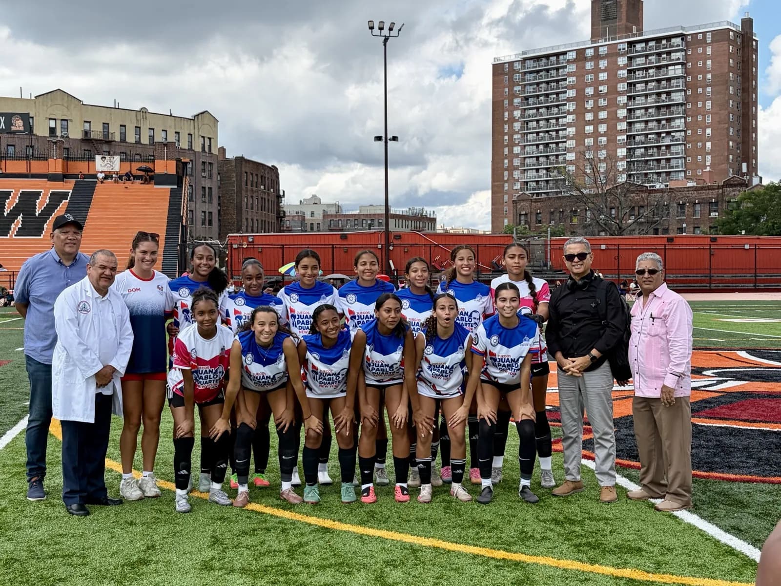 The New York squad in blue and white kits with their guest coach and Games officials at the George Washington turf field.