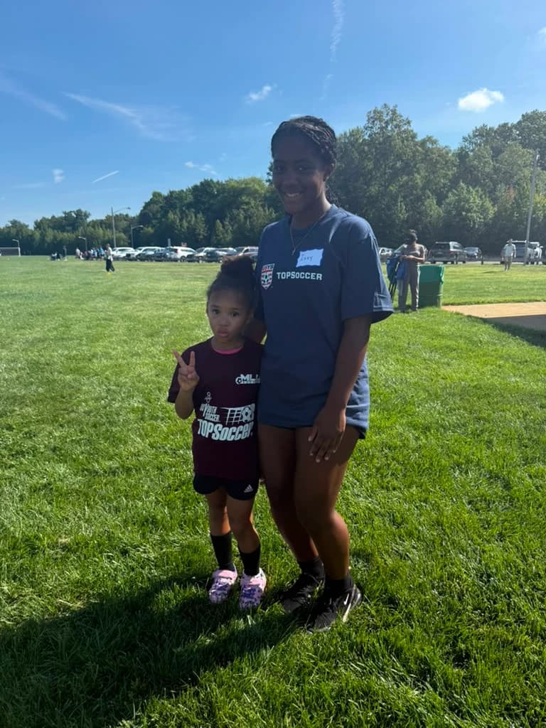 Izabella "Izzy" David in her TOPSoccer buddy shirt standing with a young TOPSoccer player on the field in Mount Laurel.